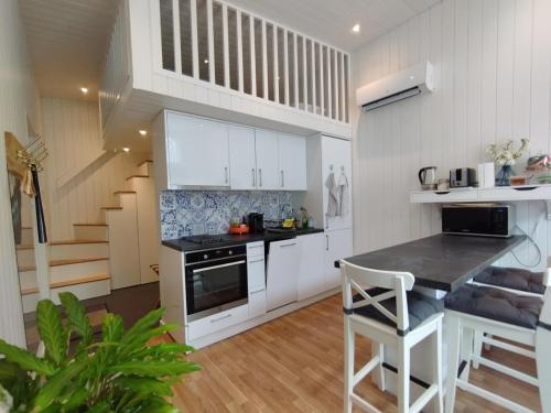 uma cozinha com armários brancos, uma mesa e uma escada em Bålsta Studio Houses em Bålsta