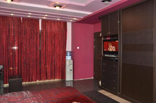 a room with purple walls and red curtains and a television at Happy Villa in Zovuni