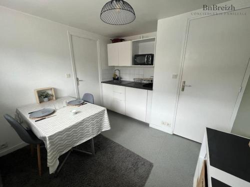 eine kleine Küche mit einem Tisch und einer weißen Küche in der Unterkunft Appart Cosy Duo in Cesson-Sévigné