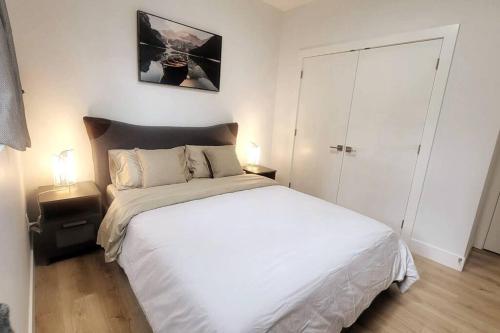 a bedroom with a large white bed with two lamps at Gorgeous 2 Bedrooms Suite Private entrane with patio-Free Parking in Maple Ridge