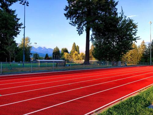 a red running track with trees and mountains in the background at Gorgeous 2 Bedrooms Suite Private entrane with patio-Free Parking in Maple Ridge District Municipality