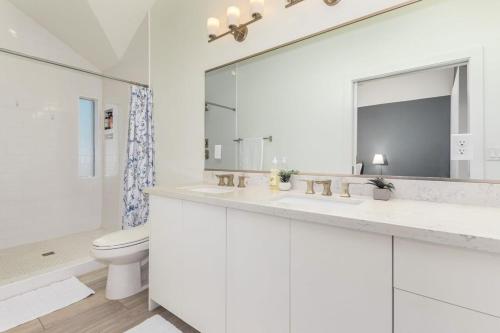 a white bathroom with a toilet and a large mirror at Urban Art Loft - Historic DT Phoenix-Chefs Kitchen in Phoenix