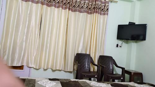 Habitación con 2 sillas y ventana con TV. en room in manali, en Manali