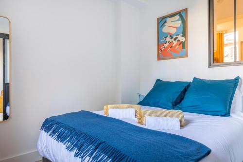 a bedroom with a bed with blue pillows at Le Petit Jaune : Centre ville T2 avec balcon in Marseille