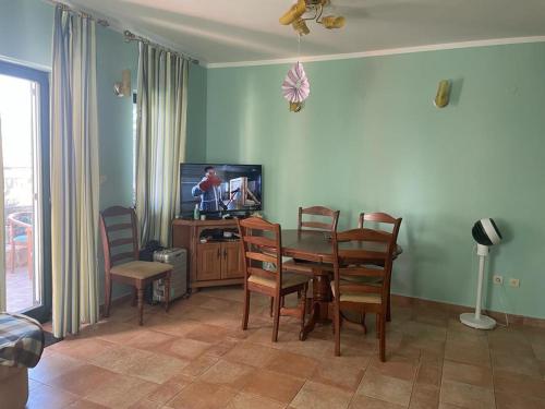 a dining room with a table and chairs and a television at Apartman green home (pool) in Radovići