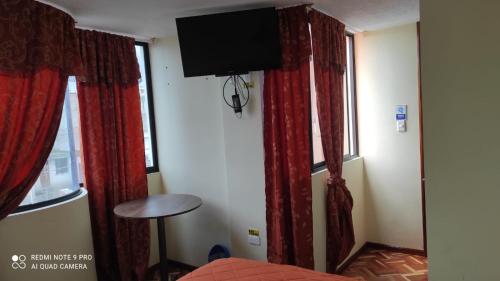 Habitación con cortinas rojas y TV de pantalla plana. en Gran Hostal Casa Luz, en Quito