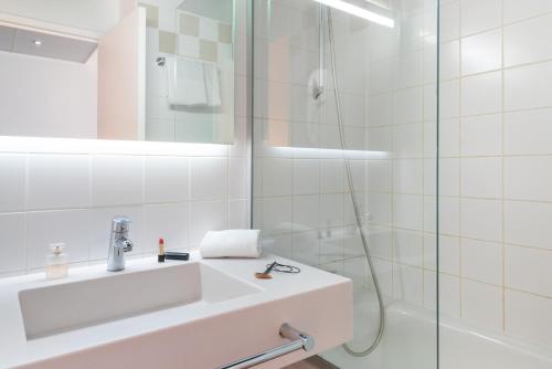 een witte badkamer met een wastafel en een douche bij ibis Styles Paris Gare de l'Est Château Landon in Parijs