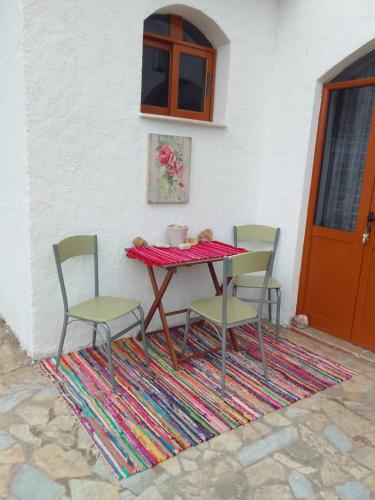 een tafel en vier stoelen op een tapijt bij Hausen Margaret's in Kuçovë