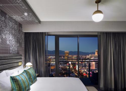 Cette chambre comprend un lit et une grande fenêtre. dans l'établissement The Cosmopolitan Of Las Vegas, à Las Vegas