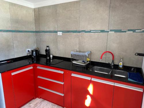 uma cozinha com armários vermelhos e um lavatório em Quincho Melincue em Melincué