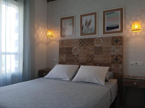 ein Schlafzimmer mit einem Bett und drei Bildern an der Wand in der Unterkunft Apartamento Pepa Bajondillo in Torremolinos