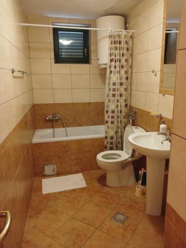 a bathroom with a toilet and a tub and a sink at Apartman Olja in Radovići