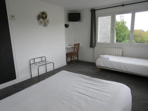 a bedroom with two beds and a table and window at hôtel de la grange in Cossé-le-Vivien