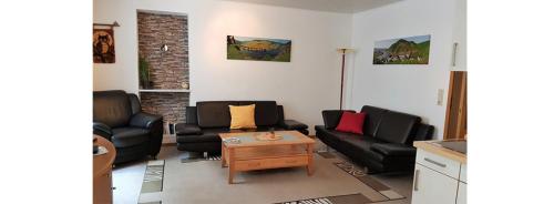 a living room with black couches and a coffee table at FeWo Alt Beilstein in Beilstein