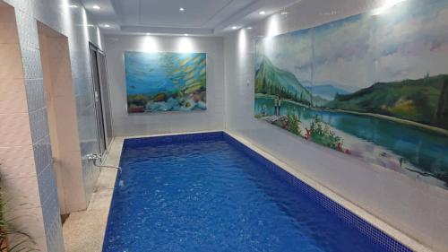 a swimming pool in a room with paintings on the wall at Piscine privative et prestations haut de gamme in Dakar