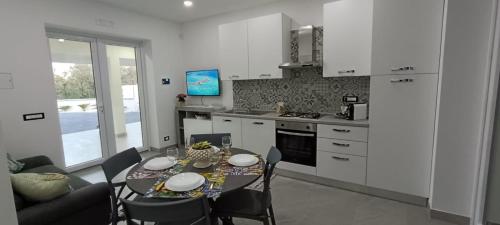 a kitchen with a table and chairs and a kitchen with white cabinets at I Coralli di Brucoli in Brucoli