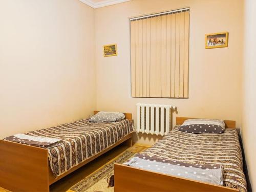 two beds in a small room with a window at Guliyev Home in Qax