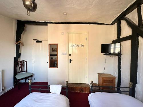 a bedroom with two beds and a chair and a door at FARRIERS ARMS in Worcester