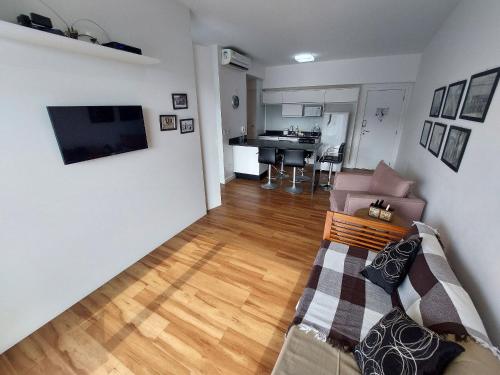 a living room with a couch and a television on a wall at Book Santos - Unlimited 1709 - Apartamento Vista Mar in Santos