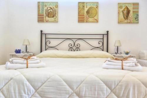 a white bedroom with two beds and two lamps at CASA CHITI TAORMINA in Taormina