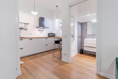 una cucina con mobili bianchi e pavimento in legno di Milano Twin Suites - Cozy Chic in Santa Sofia MM4 a Milano
