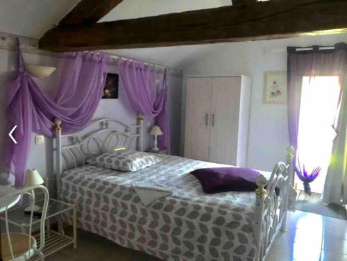 um quarto com uma cama branca e cortinas roxas em Gîte La Carillonnerie em Bossay-sur-Claise