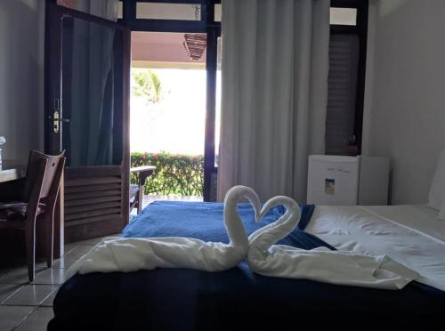 two swans are sitting on top of a bed at Hotel Praia dos Carneiros in Tamandaré