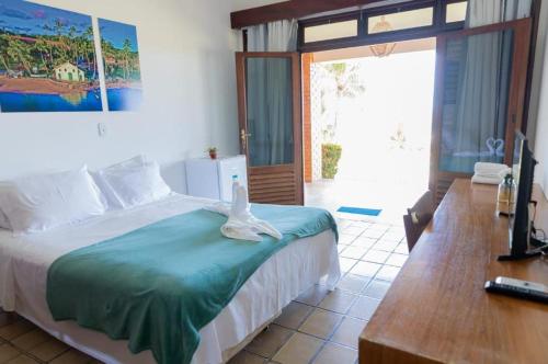 a bedroom with a bed and a desk and a television at Hotel Praia dos Carneiros in Tamandaré