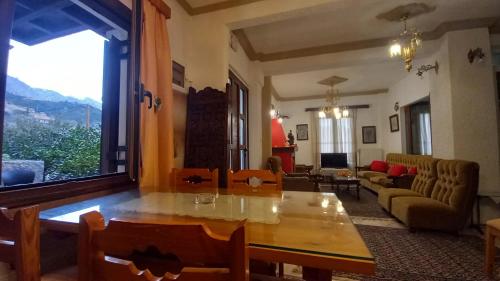 a living room with a table and a large window at ΑΡΜΟΝΙΑ MountHome awesome stay in Arachova