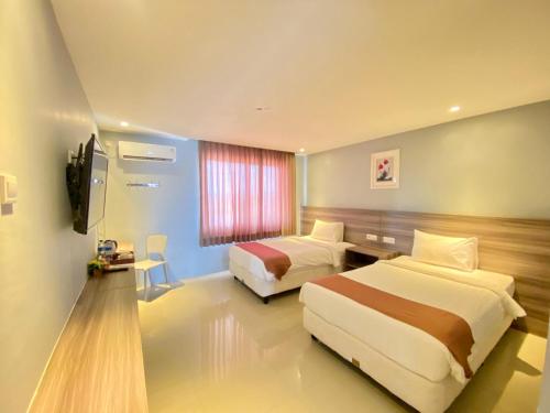 a hotel room with two beds and a television at SM Tower Hotel and Convention Berau in Tanjungredep