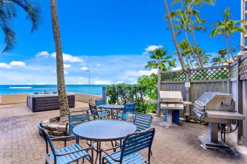 patio ze stołami i krzesłami oraz plażą w obiekcie Kahana Beach Vacation Club w mieście Lahaina