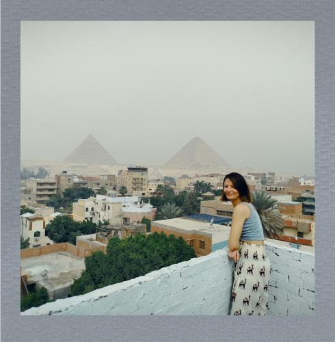 a woman standing on a roof with pyramids in the background at Eyad Pyramids view in Cairo