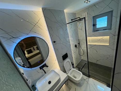 La salle de bains est pourvue d'un miroir, d'un lavabo et de toilettes. dans l'établissement Villa CACA, à Ksamil