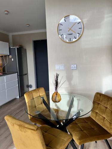 a dining room with a glass table and a clock on the wall at Casa Kashubia - Nowoczesny dom wakacyjny nad jeziorem - Cisza natura i komfort in Brzeźno Szlacheckie