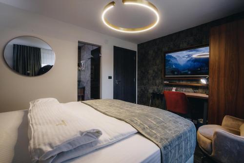 - une chambre avec un lit et une télévision murale dans l'établissement VILA RADOVIC ROOMS AND APARTMENTS, à Kragujevac