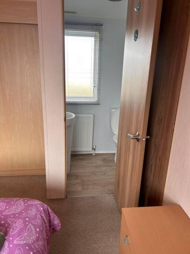 a bedroom with a door open to a bathroom at Red Lion Caravan Park, Arbroath in Arbroath