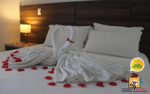 Una cama con sábanas blancas y corazones rojos. en Hotel Thermas Classic, en Marcelino Ramos