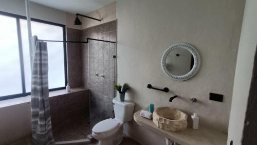 uma casa de banho com um WC, um chuveiro e um espelho. em Casa Kuxul em Mérida