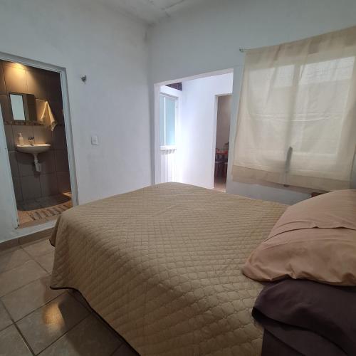 a bedroom with a bed and a bathroom with a window at Departamento Añil in San Antonio de la Cal