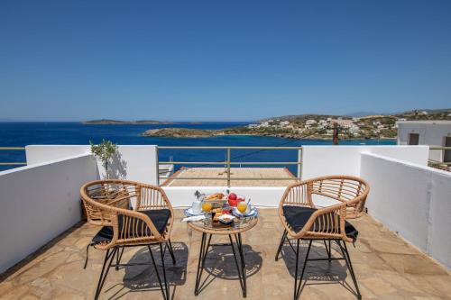 uma varanda com duas cadeiras e uma mesa com comida em Villa Fiamegou Andros em Batsi