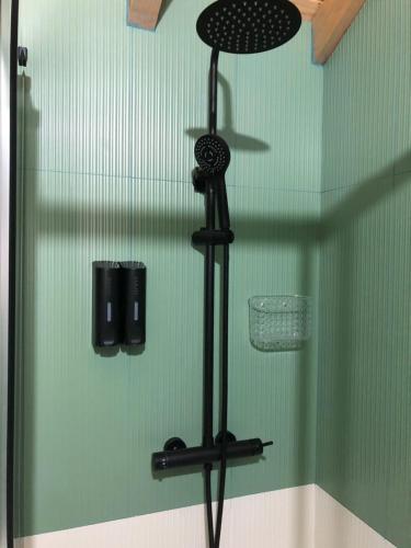 a shower with a black shower head in a green wall at Covo Residence - Casa Santiago in Vila Nova de Paiva