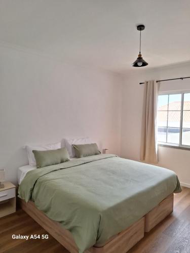 a white bedroom with a large bed and a window at Figueira's House By the Atlantic in Ponta do Sol
