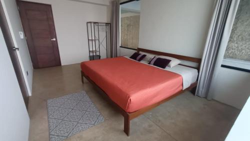 a bedroom with a bed with a red seat at Casa Kuxul in Mérida