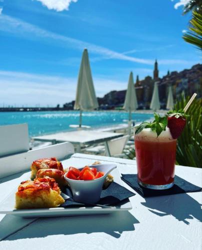 - une table avec une assiette de nourriture et une boisson dans l'établissement Le Saint Roch, à Menton