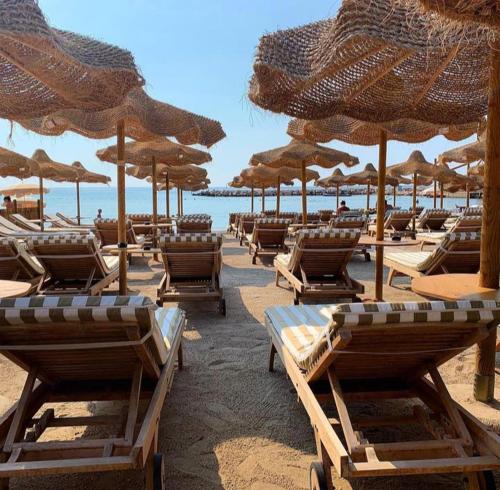 ein paar Stühle und Sonnenschirme am Strand in der Unterkunft Le Saint Roch in Menton