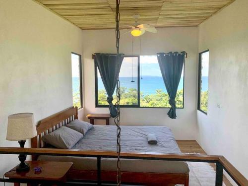 a bedroom with a swinging bed with a view of the ocean at Cotinga Nest - King Bed, Ocean View in San Pedrillo