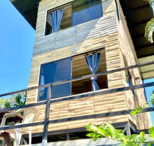 San Pedrillo的住宿－Cotinga Nest - King Bed, Ocean View，带阳台的木制房屋,配有蓝色窗帘