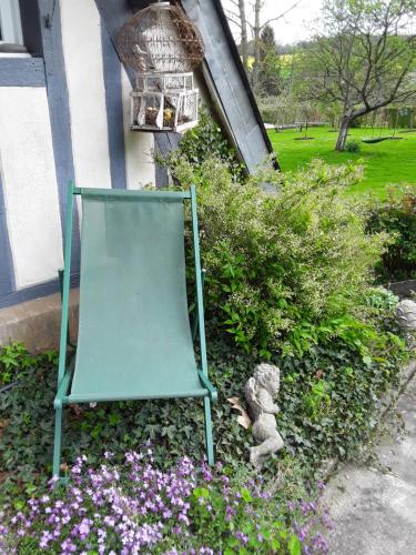 a green chair sitting in a garden with flowers at Un week-end à la campagne in Pont-Audemer