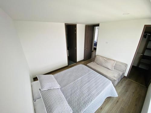 um pequeno quarto com uma cama e um sofá em Apto pent-house amoblado para estrenar em Bogotá