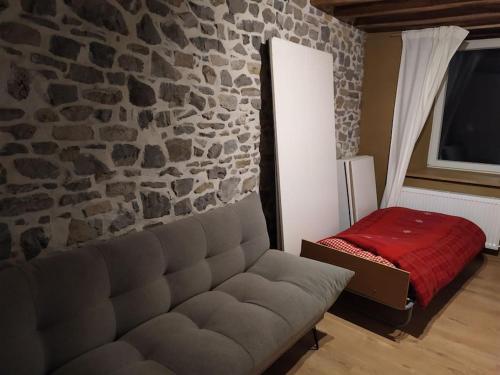 a living room with a couch and a stone wall at Ancienne ferme totalement rénové moderne à Baelen in Baelen